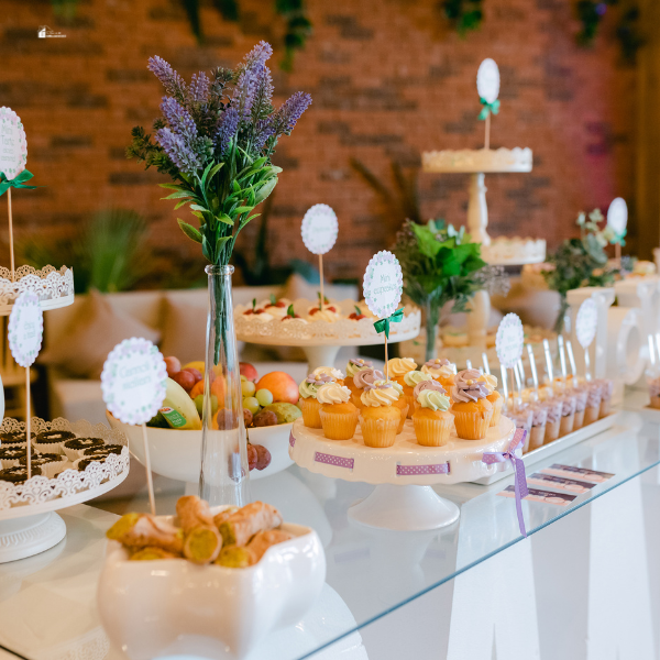 A beautifully arranged dessert table with cupcakes, fruits, and decorative flowers, perfect for a special event.