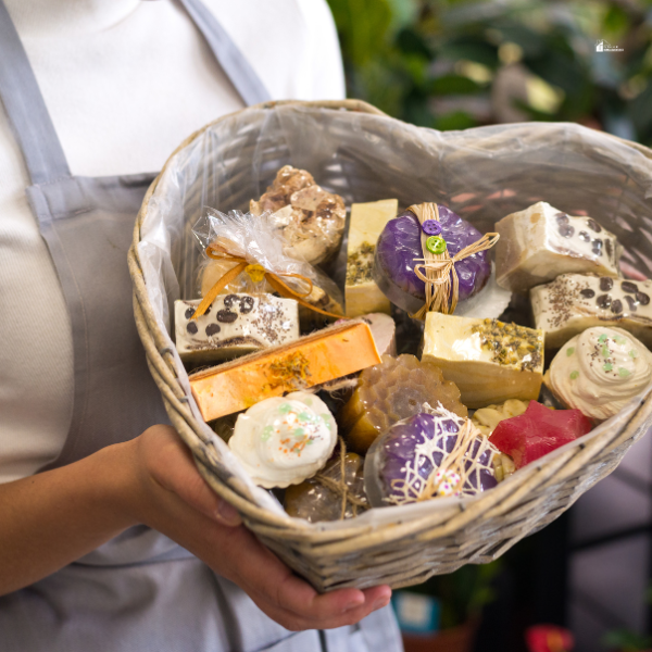  A person holding a basket filled with various handcrafted soaps and bath products.