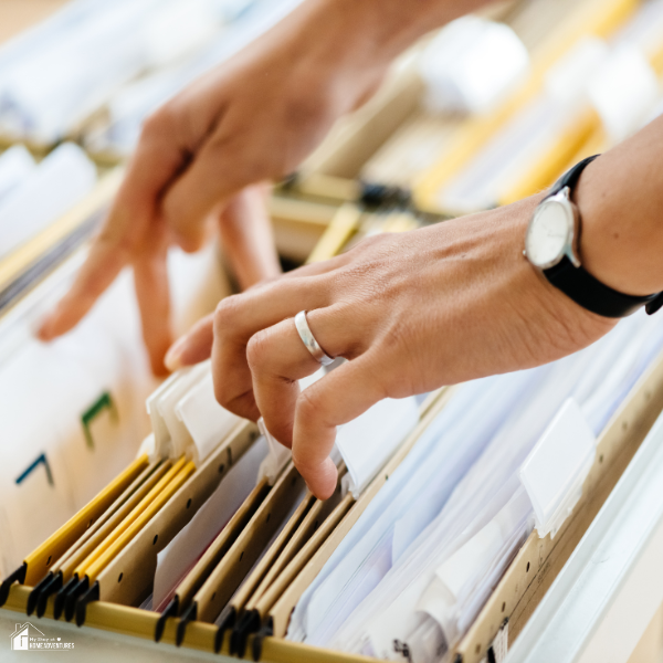 A person organizing paperwork in a filing system, highlighting how proper document management can help improve financial organization.