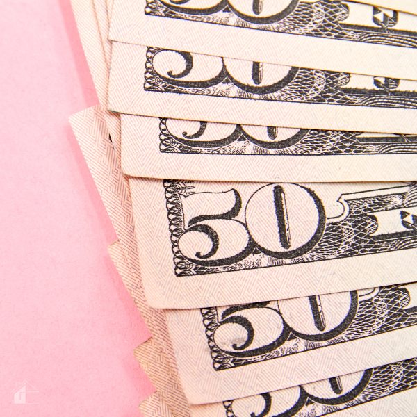 Stack of fifty-dollar bills on a pink background representing easy money-saving strategies and budgeting tips to save $50 each week.