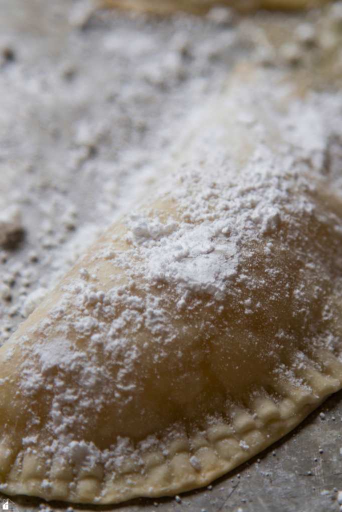 Empanada dusted with powdered sugar, filled with sweet guava and cheese, ready to be baked for a delicious dessert or snack.