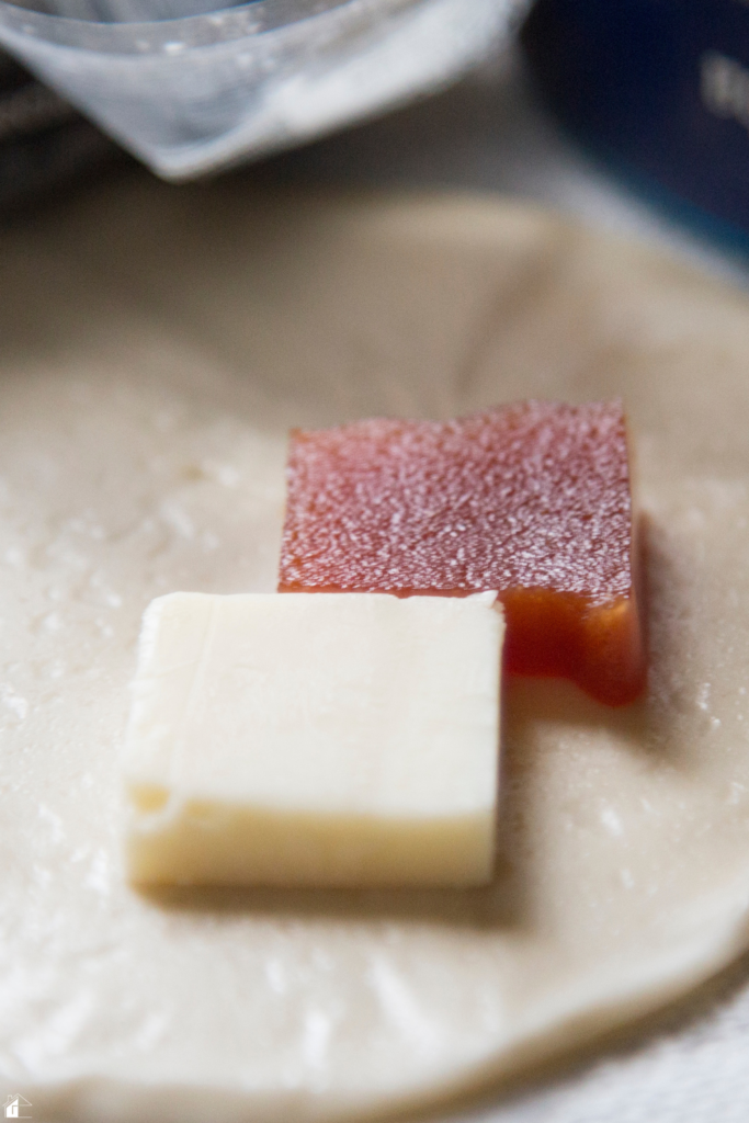 Guava paste and a slice of sharp cheese placed on an empanada disc, ready to be folded and baked into a sweet and savory empanada.