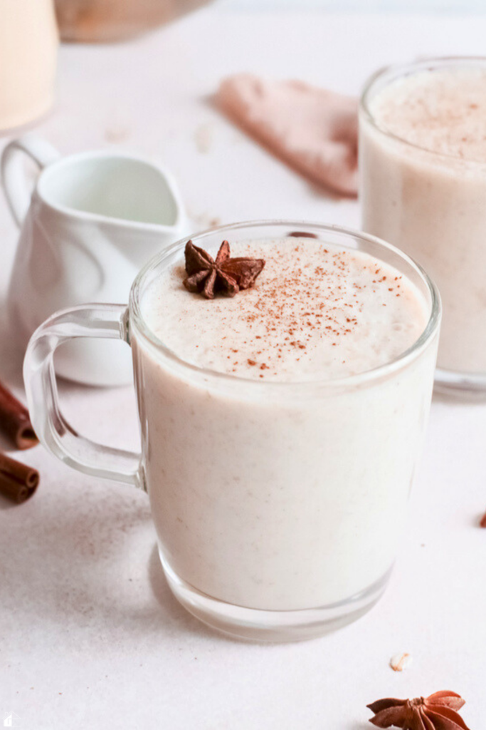 A creamy Mexican oatmeal drink, Atole de Avena, served warm in a glass mug, topped with a sprinkle of cinnamon and a star anise garnish, perfect for a cozy winter breakfast or comforting evening beverage.