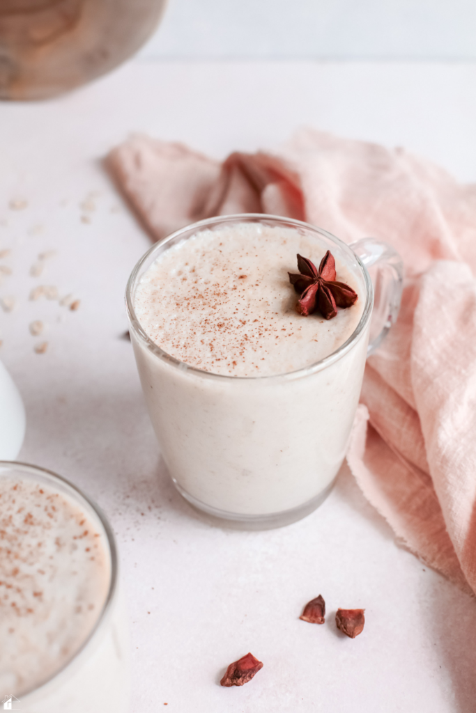 A creamy Atole de Avena, a traditional Mexican oatmeal drink, served in a glass mug with cinnamon and star anise, perfect for a cozy winter morning or a comforting evening beverage.