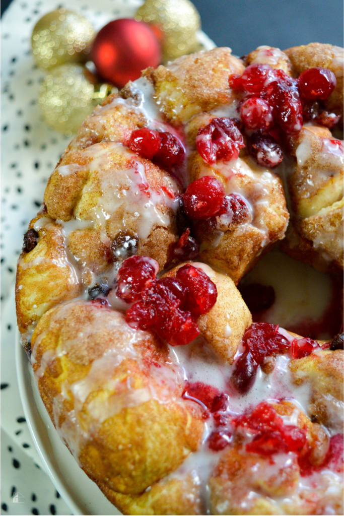 Golden brown cranberry raisin monkey bread topped with vibrant cranberries and a sweet glaze, perfect for holiday baking and festive Christmas breakfast ideas.