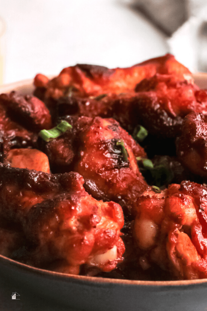 A close-up of crispy air fryer chicken wings coated in a sticky bourbon honey glaze, garnished with chopped green onions, perfect for game day appetizers, easy air fryer recipes, and quick party snacks.