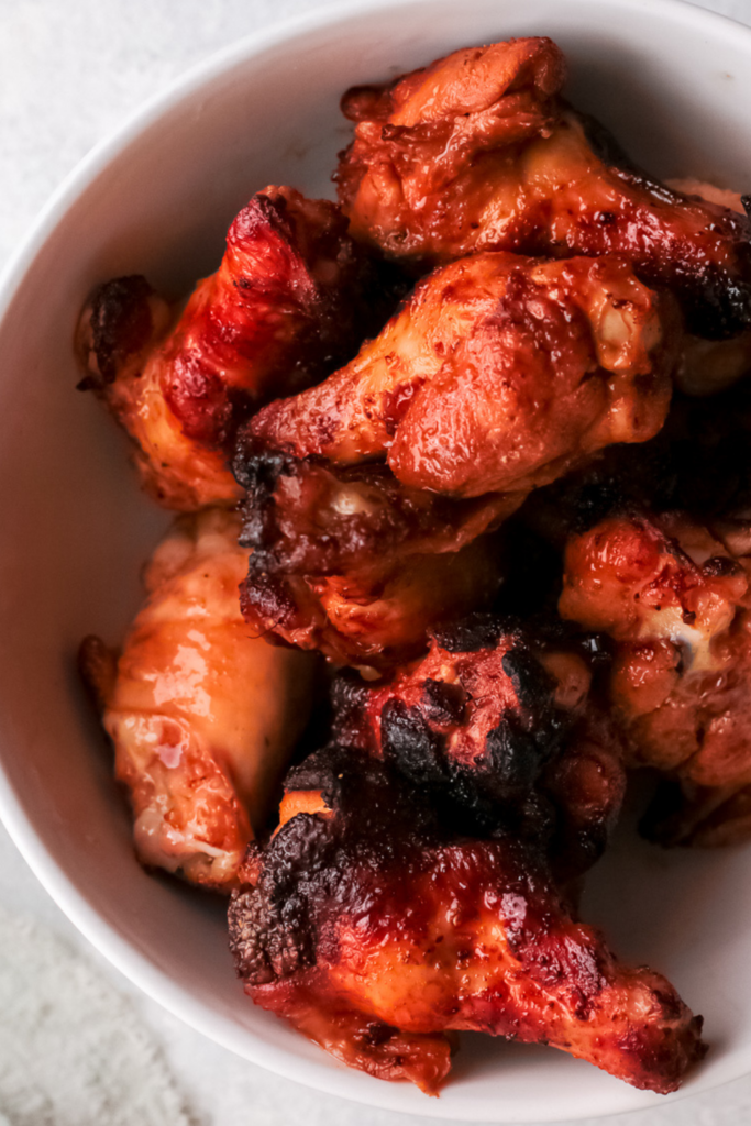 A close-up of crispy bourbon honey wings in a white bowl, coated in a caramelized, sticky glaze, perfect for air fryer chicken wings, easy appetizers, and game day snacks.