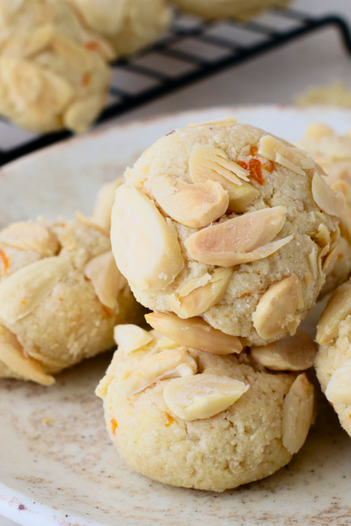 Close-up of freshly baked Greek Almond Cookies topped with slivered almonds and hints of orange zest, showcasing their crispy texture and perfect for a gluten-free treat.