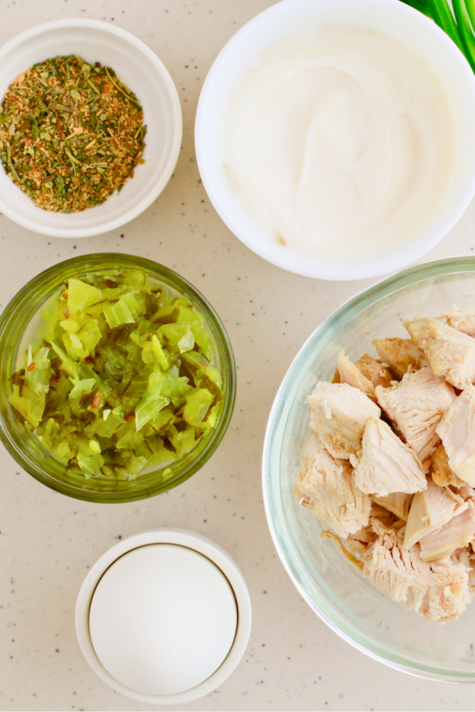 Ingredients for an easy chicken salad recipe, including cooked chicken, mayonnaise, relish, hard-boiled egg, and seasoning, arranged on a countertop—perfect for making a creamy and delicious chicken salad for sandwiches or meal prep.