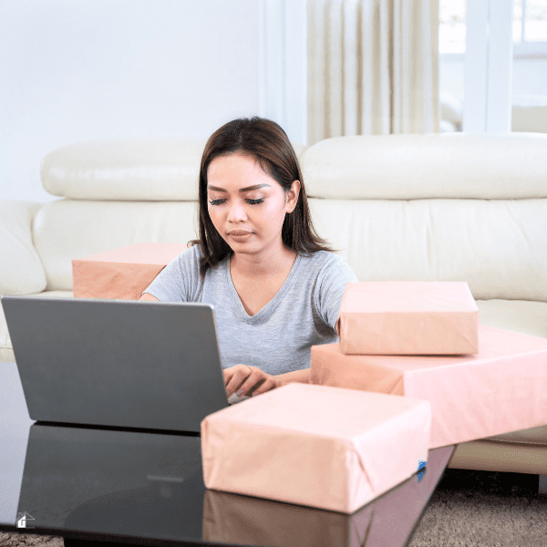 woman using a laptop and reselling online with boxes next to her. 