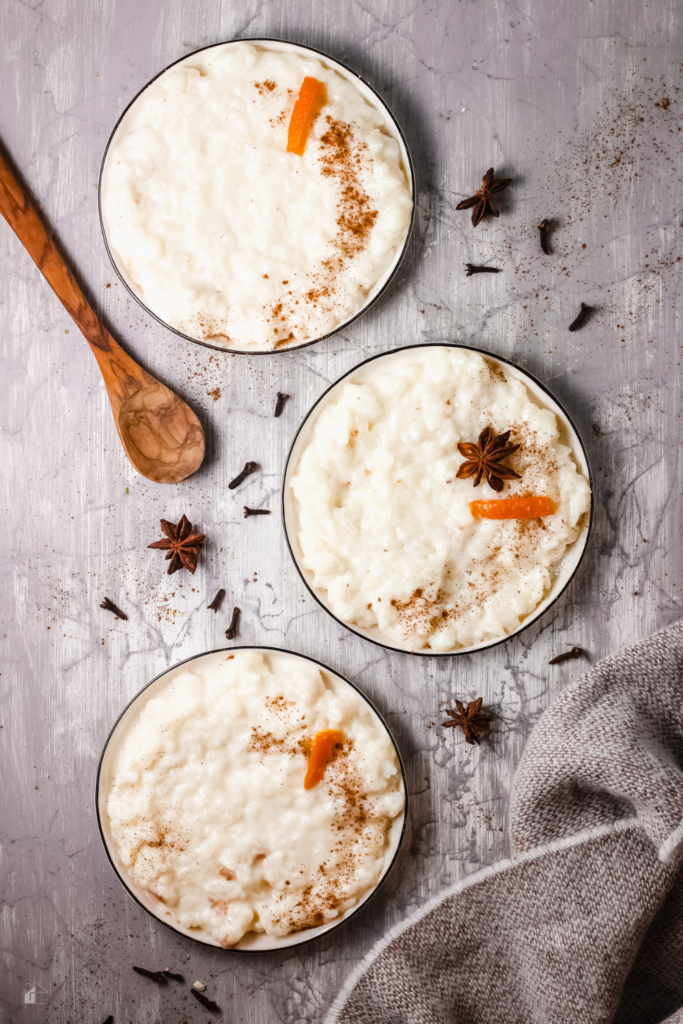 Top-down view of three bowls of creamy Puerto Rican Arroz con Leche, garnished with cinnamon, orange peel, and star anise, perfect for a traditional Latin American dessert or a comforting holiday treat.