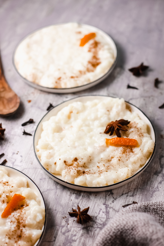 Creamy Puerto Rican Arroz con Leche topped with cinnamon, orange peel, and star anise, served in a white bowl, showcasing a traditional rice pudding perfect for holiday desserts and comfort food lovers.