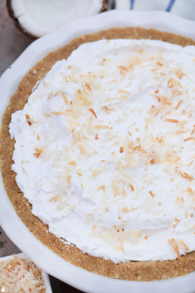 A finished Coconut Rum (Coquito) Cream Pie topped with whipped cream and toasted coconut, set in a graham cracker crust, perfect for holiday gatherings and festive Puerto Rican dessert recipes.