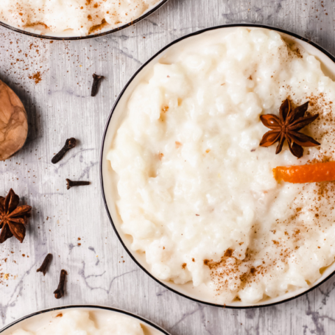 Top-down view of a bowl of creamy Arroz con Leche, garnished with cinnamon, orange peel, and star anise, highlighting the traditional Puerto Rican dessert as a comforting and classic Latin American dish.