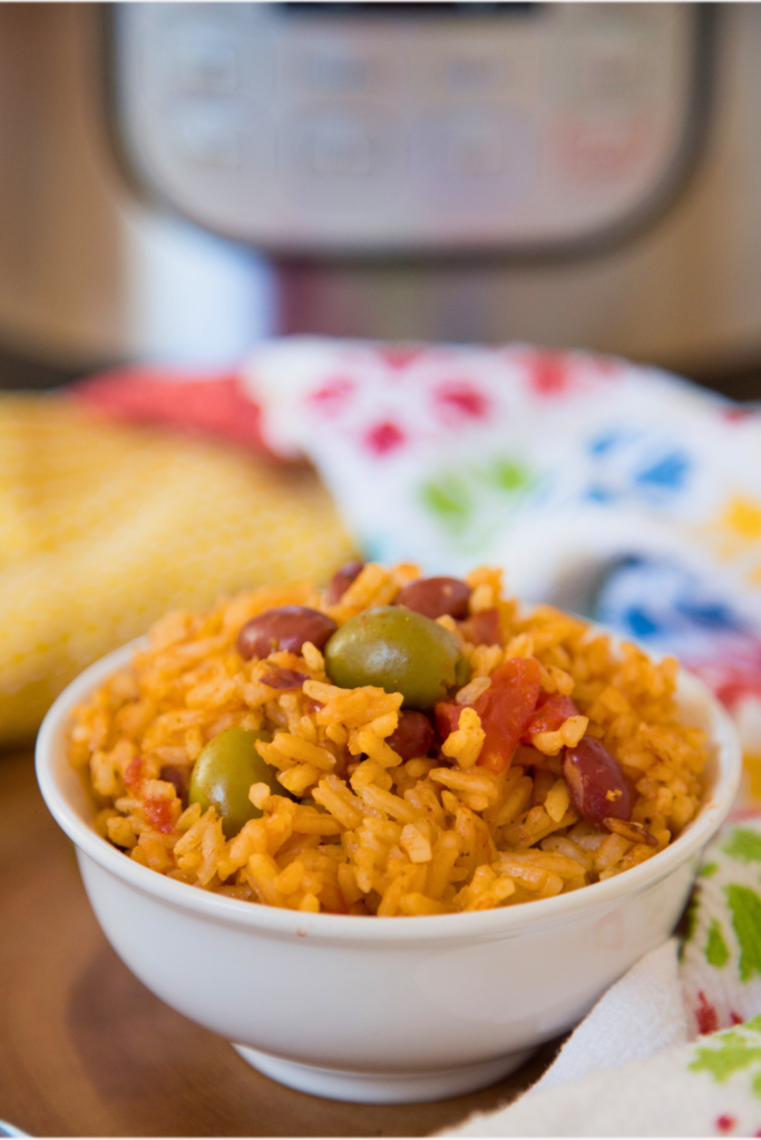 Bright and colorful bowl of Instant Pot rice and beans with red beans, green olives, and vibrant Puerto Rican seasonings, perfect for quick and easy family dinners or weeknight meals.