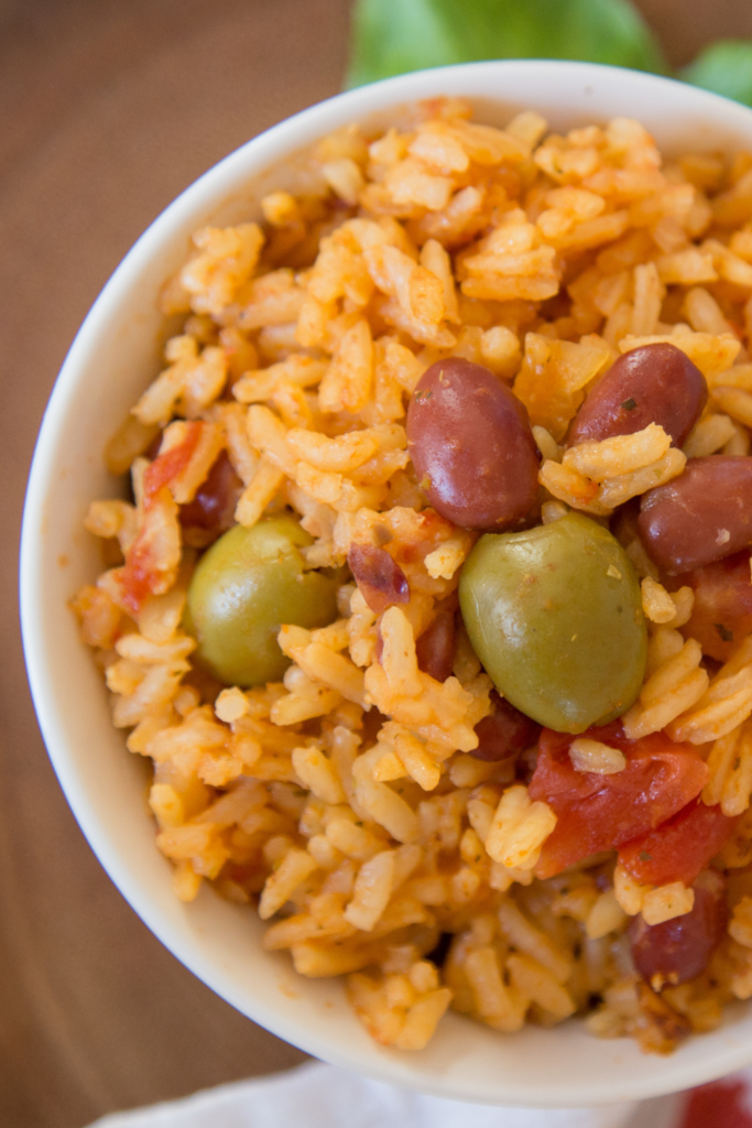 Close-up of a bowl of Instant Pot Puerto Rican rice and beans featuring fluffy seasoned rice, tender red beans, and briny green olives, showcasing a vibrant and hearty dish perfect for quick family dinners.