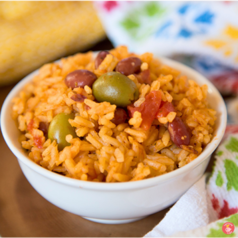 A vibrant bowl of Instant Pot Puerto Rican rice and beans featuring fluffy yellow rice, tender red beans, green olives, and bold seasonings, perfect for quick weeknight dinners. 🌿