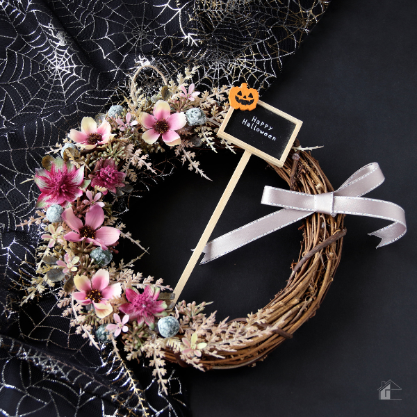 Elegant Halloween wreath with pink flowers, ribbon, and a "Happy Halloween" sign, ideal for non-crafters seeking stylish and easy Halloween decor ideas.