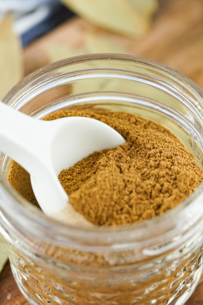 A jar of homemade apple pie spice mix with a spoon, perfect for adding to fall dessert ideas. Learn how to make apple pie spice for your favorite pie spice recipe and homemade dry mixes.