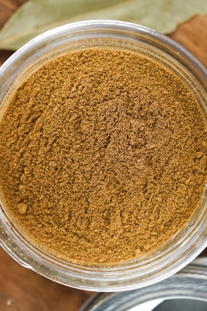 Close-up view of a jar filled with finely ground homemade apple pie spice, perfect for adding to your favorite fall dessert ideas. Learn how to make apple pie spice for homemade dry mixes.