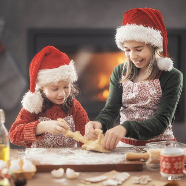 Two children wearing Santa hats and baking cookies together, representing affordable and fun holiday activities for families during Christmas on a budget.