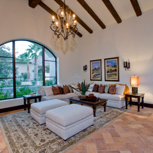 A cozy living room with a large arched window, wood-beam ceiling, and rustic decor, perfect for incorporating nature-inspired art ideas.