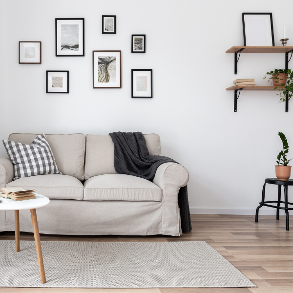 A bright, minimalist living room featuring a neutral sofa, gallery wall, and simple plants, showcasing how to add outdoor-themed art to small spaces.