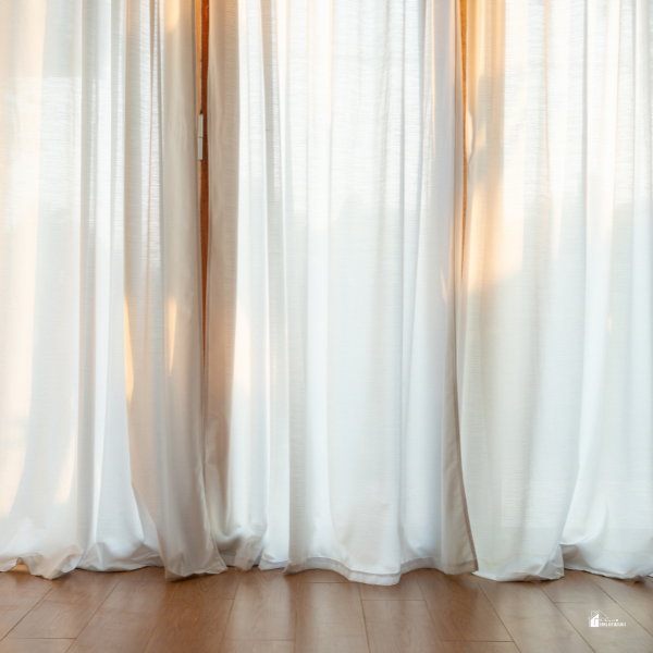 Sheer white curtains glowing softly in natural sunlight, illustrating a calming and elegant solution for creating a quiet and peaceful home.