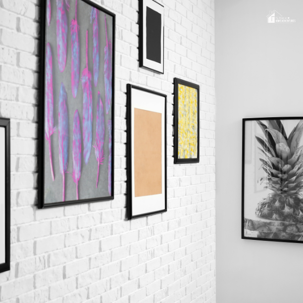 Gallery wall with framed artwork on a white brick wall, showcasing affordable home decor ideas for stylish living spaces.