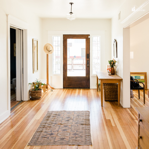 Welcoming entryway with natural wood flooring, a rustic rug, and minimal decor, ideal for home improvement inspiration on a budget.