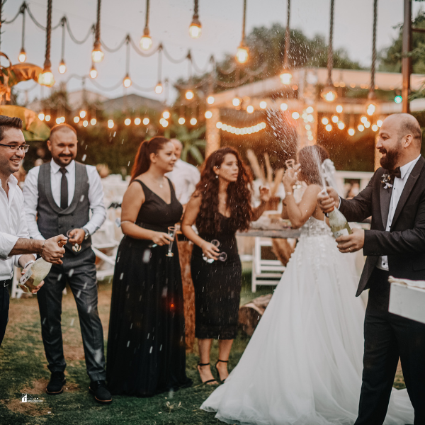 A lively garden party featuring guests dressed in formal attire, celebrating under string lights with champagne, perfect for hosting an elegant outdoor event.