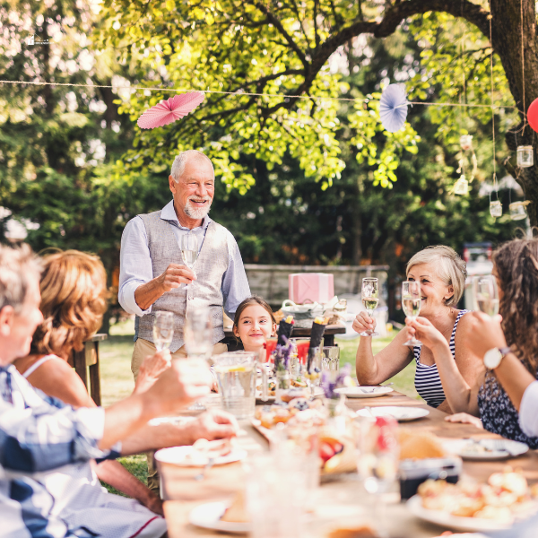 A multi-generational family enjoying a toast at an outdoor garden party, surrounded by festive decorations and greenery, highlighting ideas for casual outdoor entertaining.