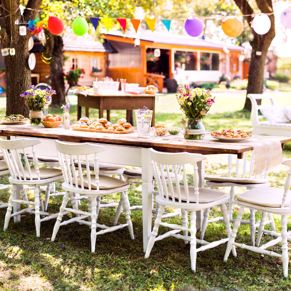 A vibrant garden table setup with colorful decorations, floral centerpieces, and festive food, showcasing inspiration for hosting a cheerful outdoor party.