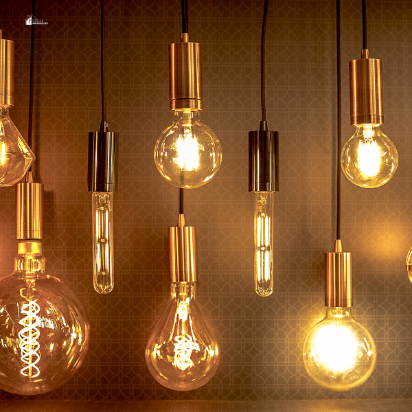 A collection of hanging light bulbs with varied shapes and brass accents, emphasizing creative and innovative lighting designs using plastic materials.