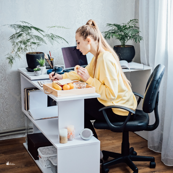 A parent multitasking at a home office with a meal and laptop, illustrating work-life balance for career growth and family priorities.