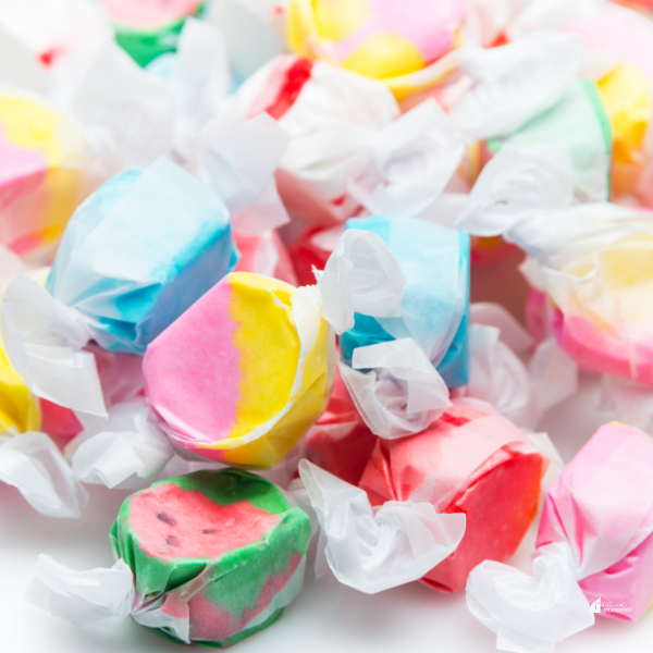 A close-up of colorful wrapped taffy candies in a variety of bright pastel colors, perfect for festive holiday treats or fun candy gift ideas.