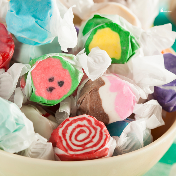 A bowl filled with assorted taffy candies in vibrant colors and patterns, a festive addition to holiday celebrations and candy buffets.