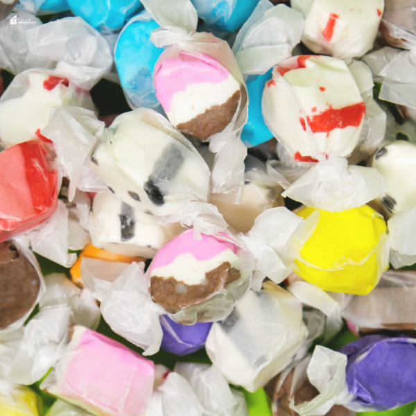 A pile of assorted wrapped taffy candies in unique flavors and colors, ideal for holiday snacking or creative gift ideas.