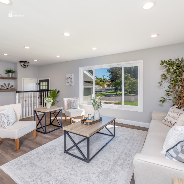 A chic, minimalist living room with neutral-toned furniture, a light gray rug, and greenery enhancing the space’s airy feel.