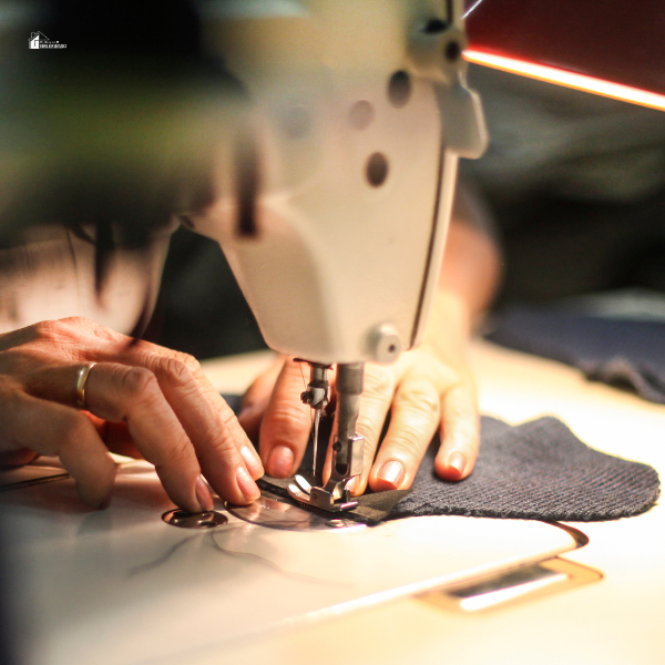 Close-up of a person’s hands guiding fabric through a sewing machine while working on a project.