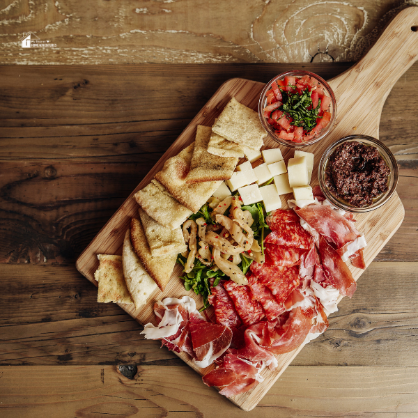 A rustic wooden charcuterie board with cured meats, cheeses, bread, and dips, providing inspiration for creating a classic French charcuterie spread.