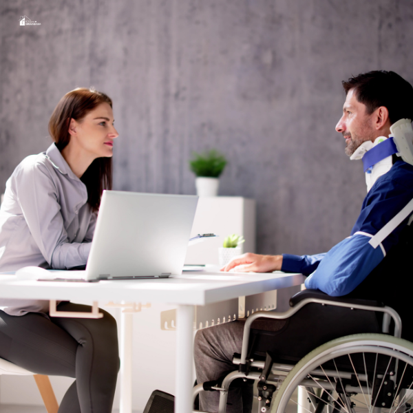 A professional woman discusses legal matters with a man in a wheelchair, highlighting support for personal injury claims and recovery processes.