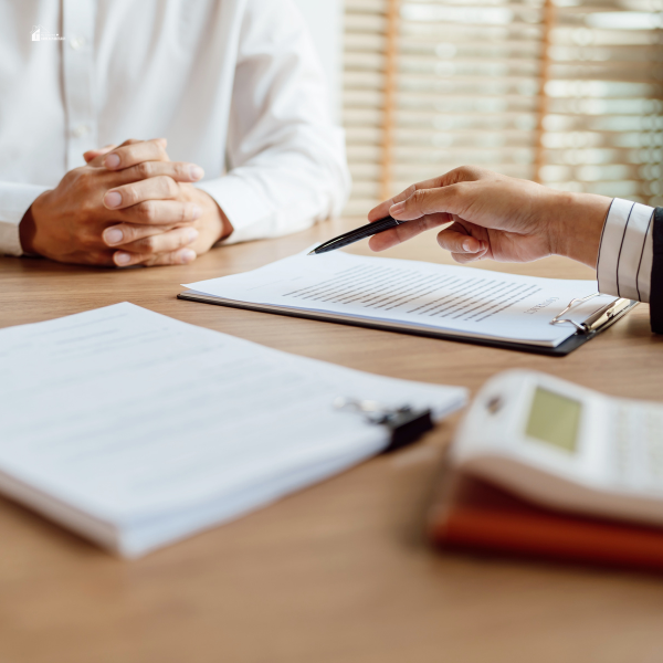 Close-up of two people discussing legal documents with a pen and clipboard, illustrating negotiations or review of personal injury claims.