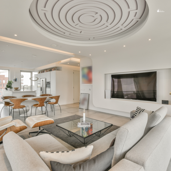 A modern living room with a unique ceiling design, sleek furniture, and an open-concept layout connected to the dining area.