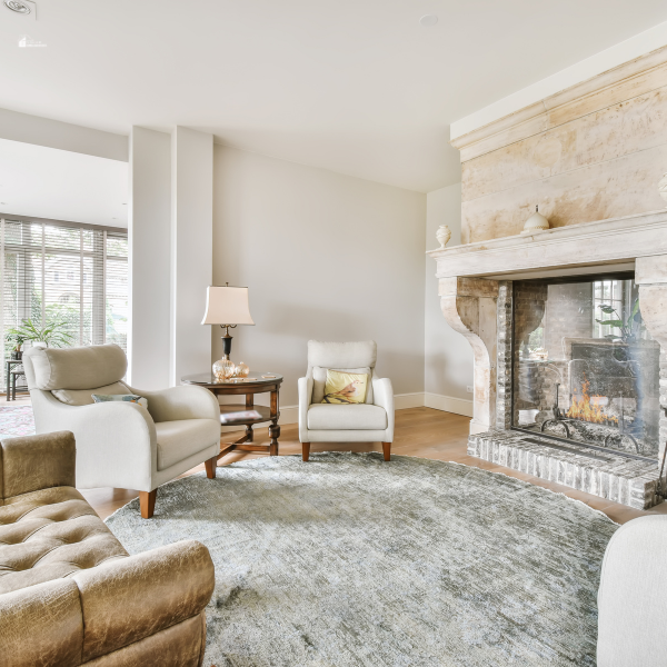 A cozy living room with a rustic stone fireplace, plush seating, and a soft area rug for an elegant yet comfortable look.