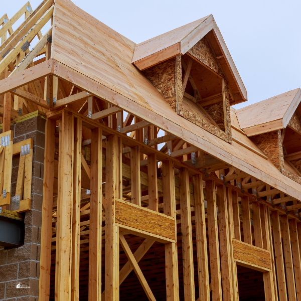 A partially built house with wooden framing and dormer windows, highlighting the early stages of exterior construction.