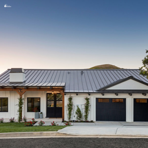 A modern single-story home with a black metal roof, wooden accents, and a well-manicured front yard at sunset.