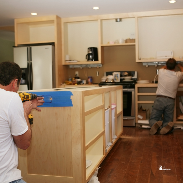 Two workers constructing a kitchen island and cabinets, illustrating the kitchen remodeling process.