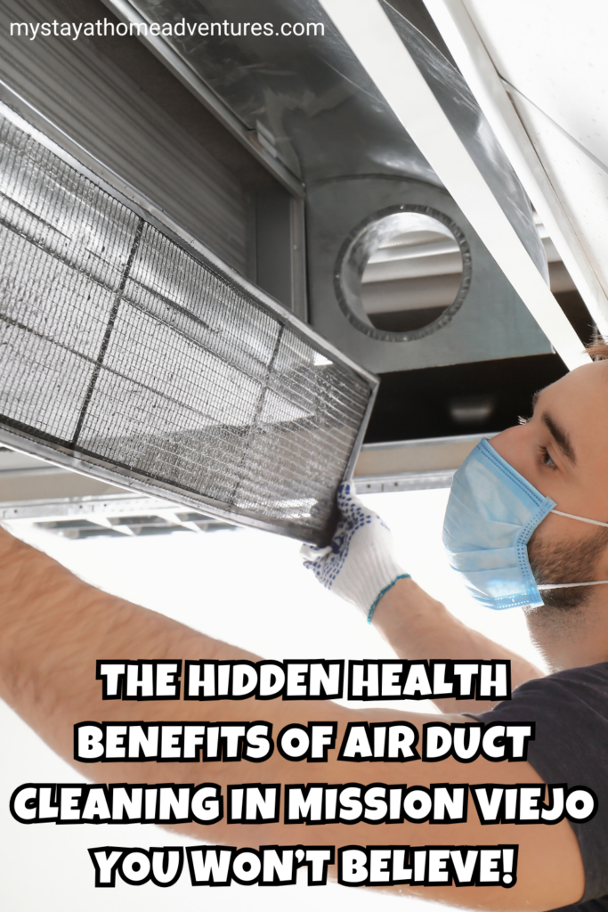 A technician wearing a face mask and gloves removes a dirty air filter from a ventilation system for cleaning.