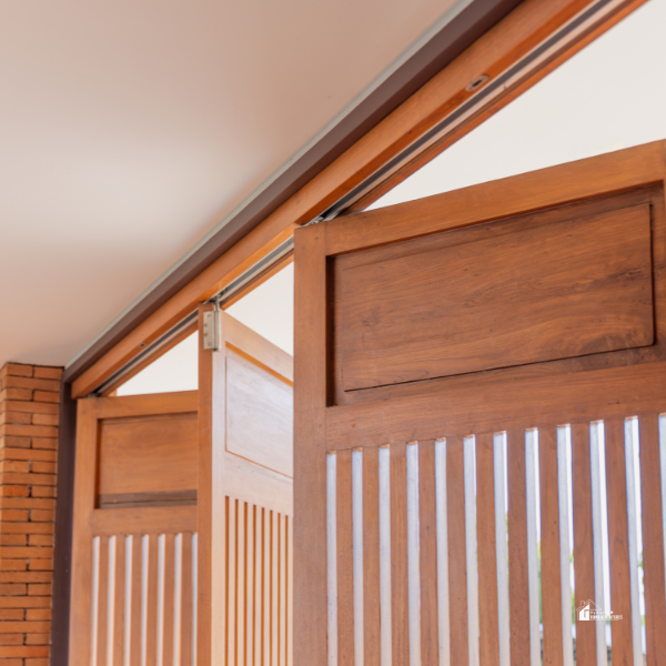 A close-up of wooden bifold doors with vertical slats and a sliding track system, highlighting a stylish home design element.